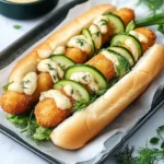 Hot Dog mit Fischstäbchen, Gurken und Dill-Senf-Sauce First Image First Image